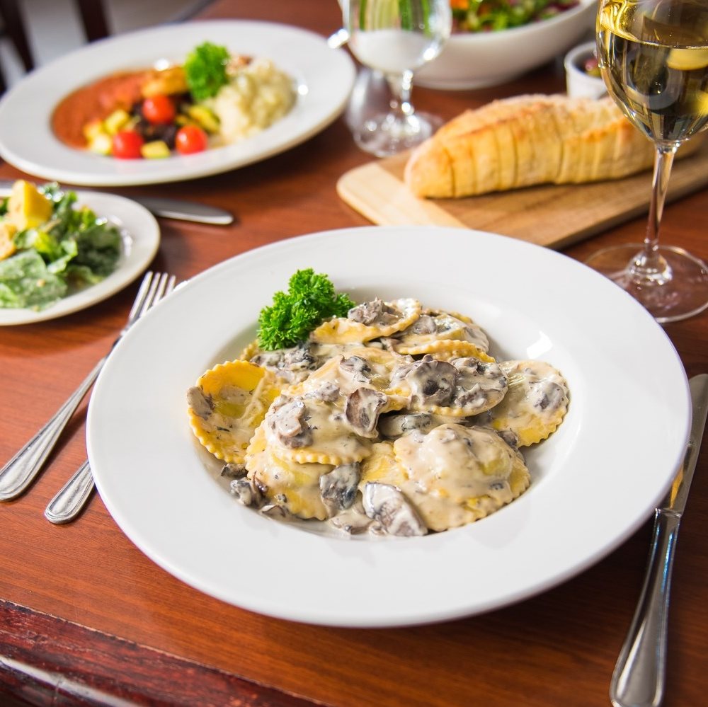 a dining table set with large bowls of creamy pasta dishes at Farina North Bay.