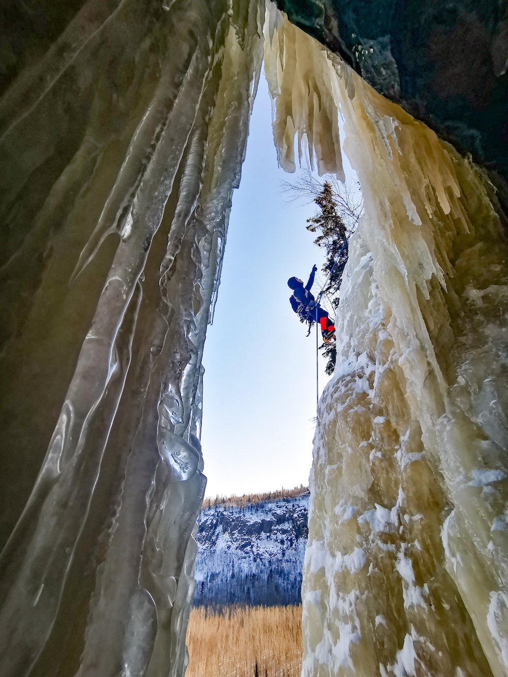 Person climbing up frozen waterfall