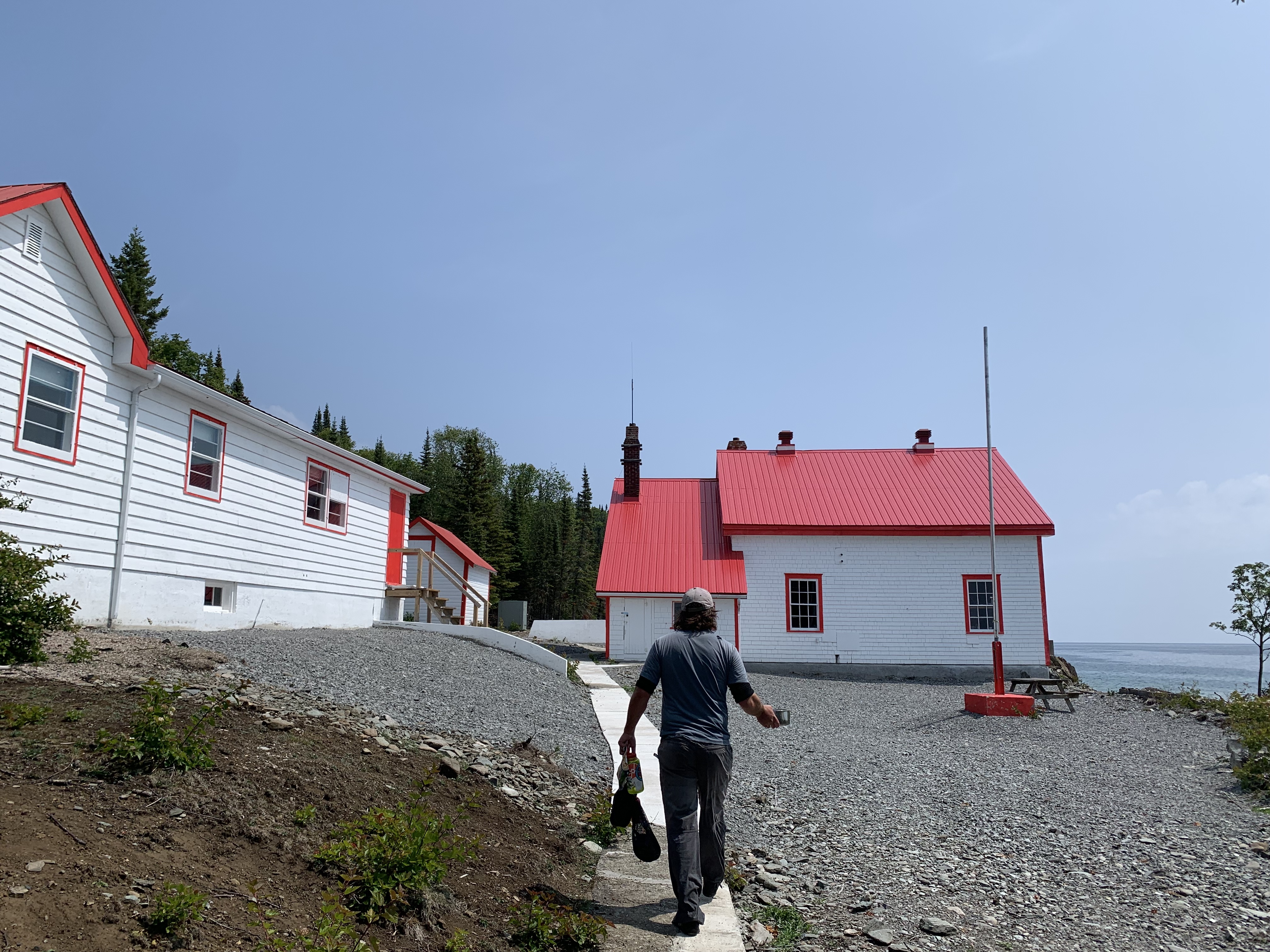 Man walking up to red and white lighthouse buildings