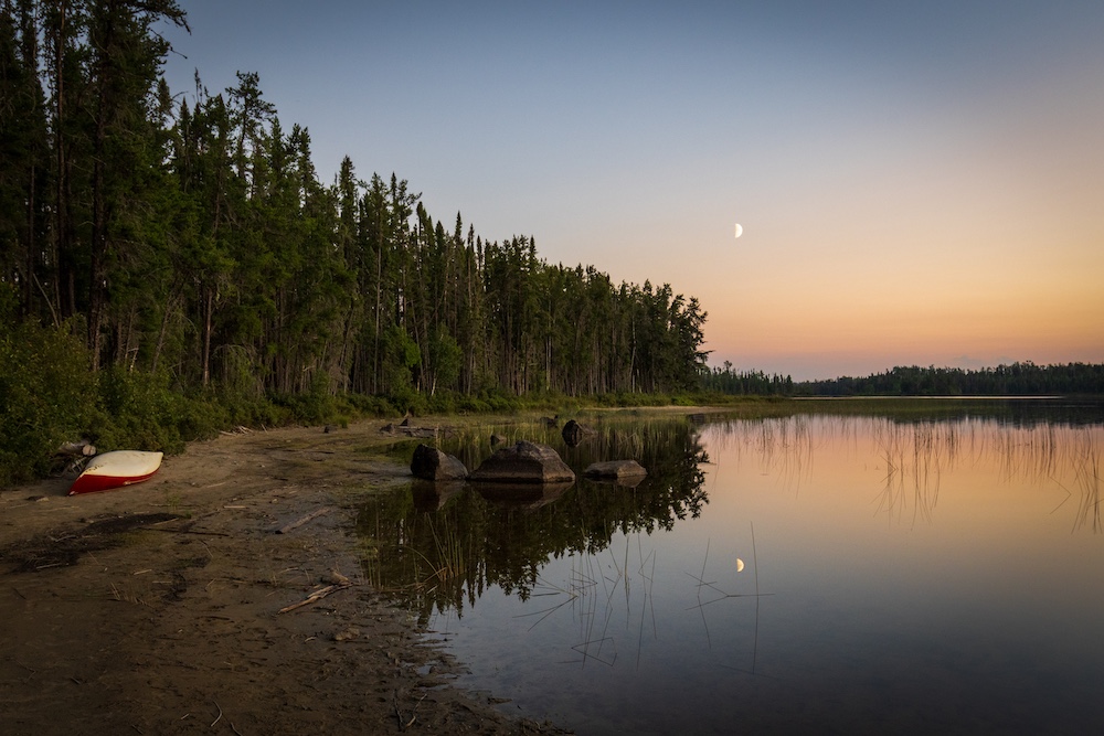 Canoe pulled up on shore at sunset