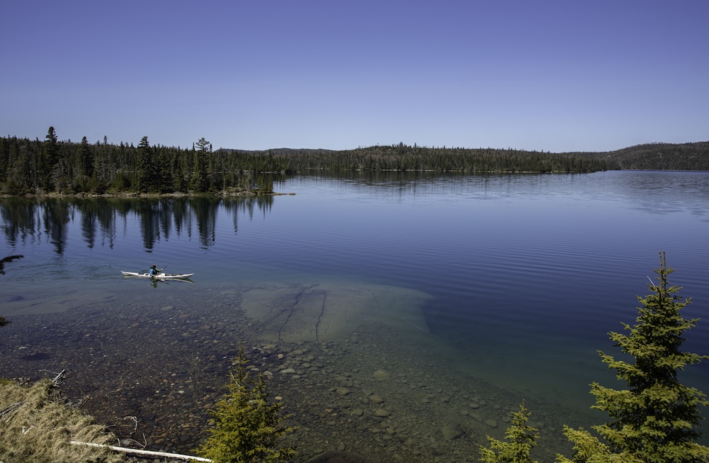 Sea kayaker on lake where you can see the lake bottom