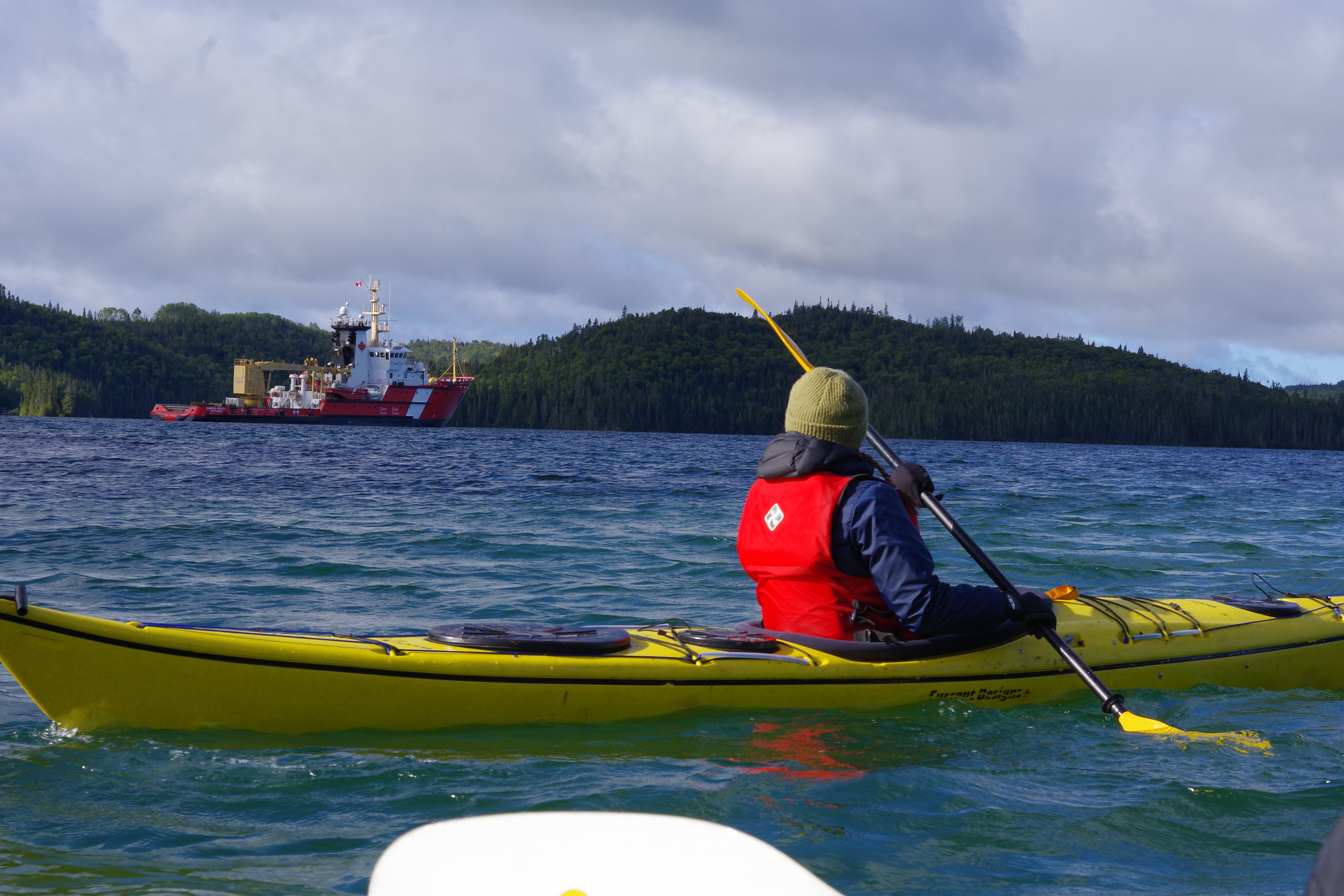 Woman in sea kayak with big ship in background
