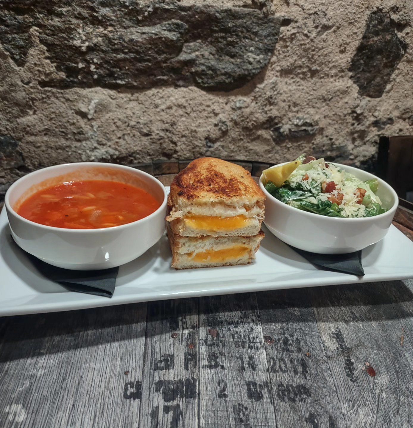 a long retangular plate with tomoto soup, a grilled cheese sandwich and caesar salad at Block Public House in North Bay.