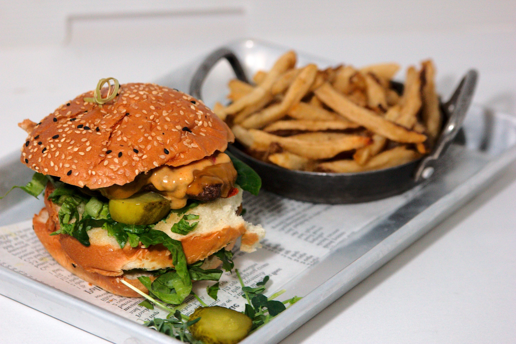 a hamburger topped with fresh vegetable and a side of fries from Cecil's Brewhouse North Bay.