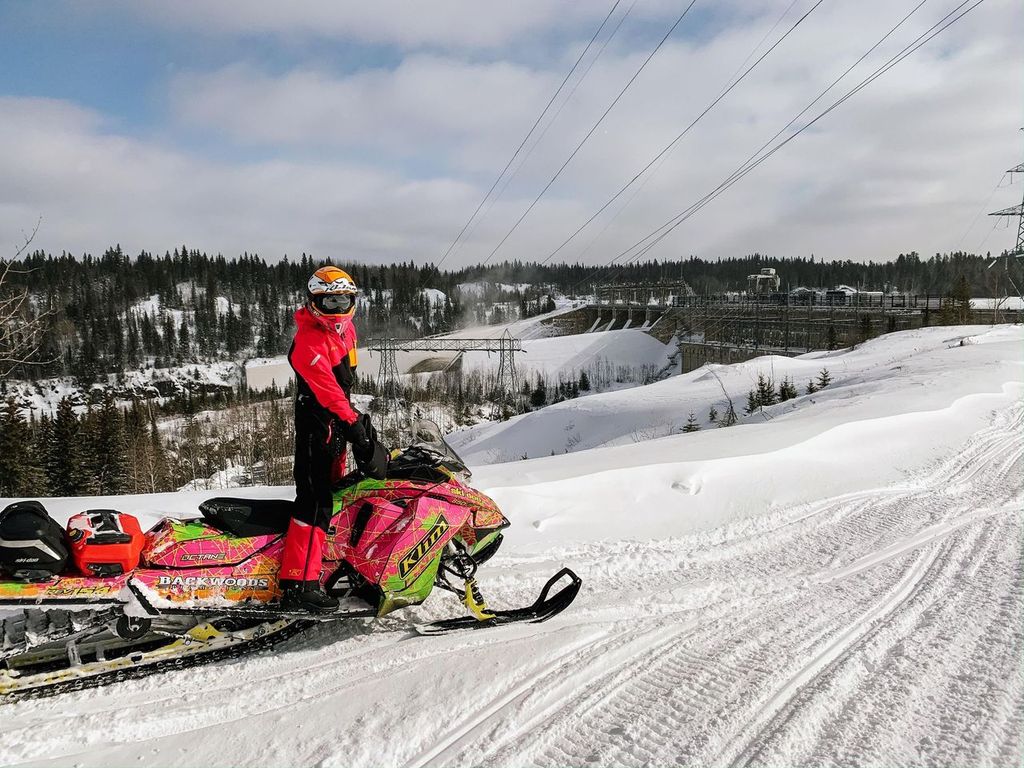 a snowmobiler looks out over a snowy forested valley in Northeastern Ontario.