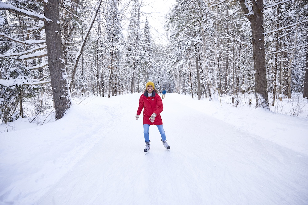 Person skating on frozen trail through the woods.
