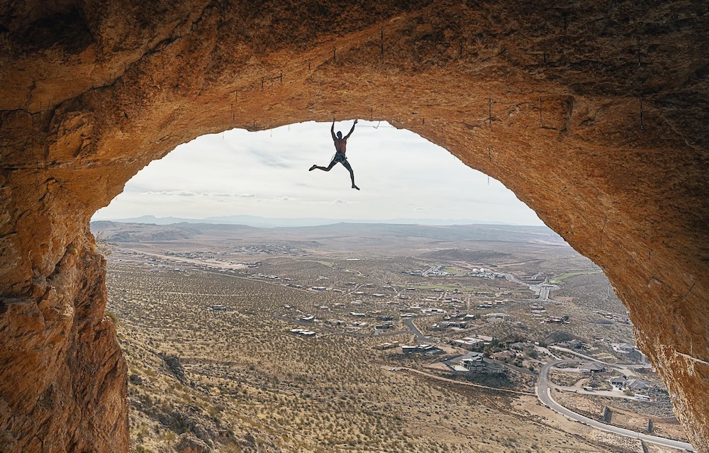 Rock climber hanging from an arch