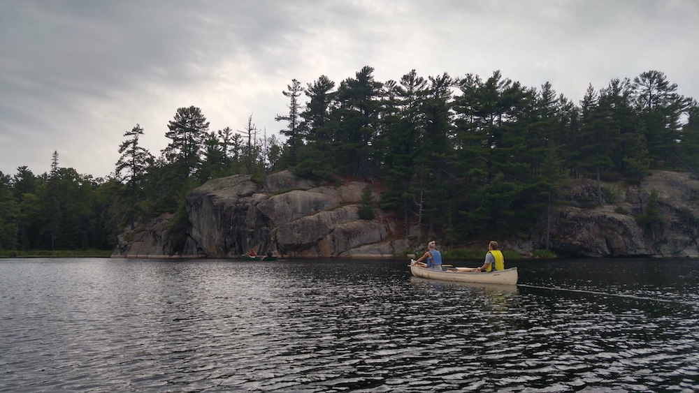 Canoe with two people in it paddling across lake