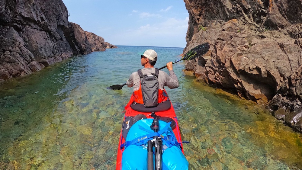 Man sea kayaking through narrow passage