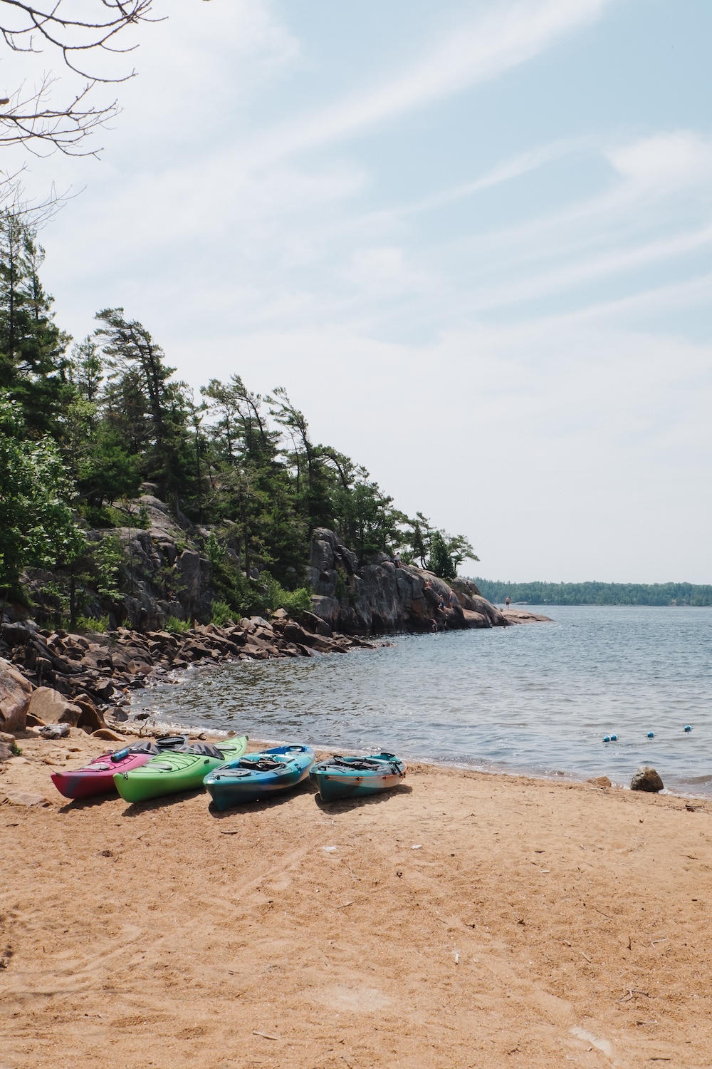 Colourful kayaks lined up on beach next to lake