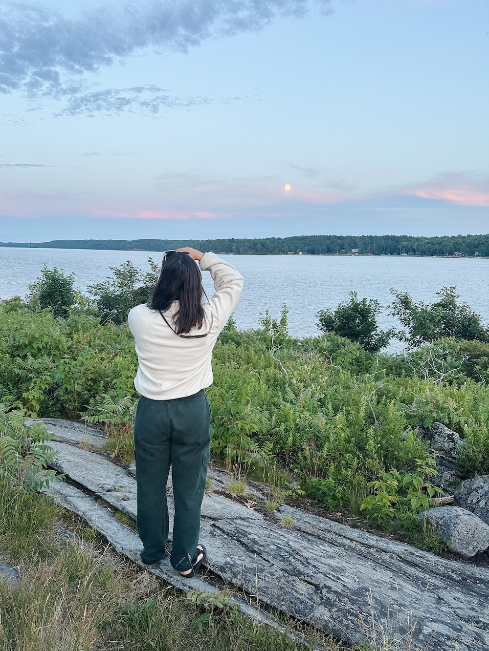 Woman taking a photo of sunset across the water