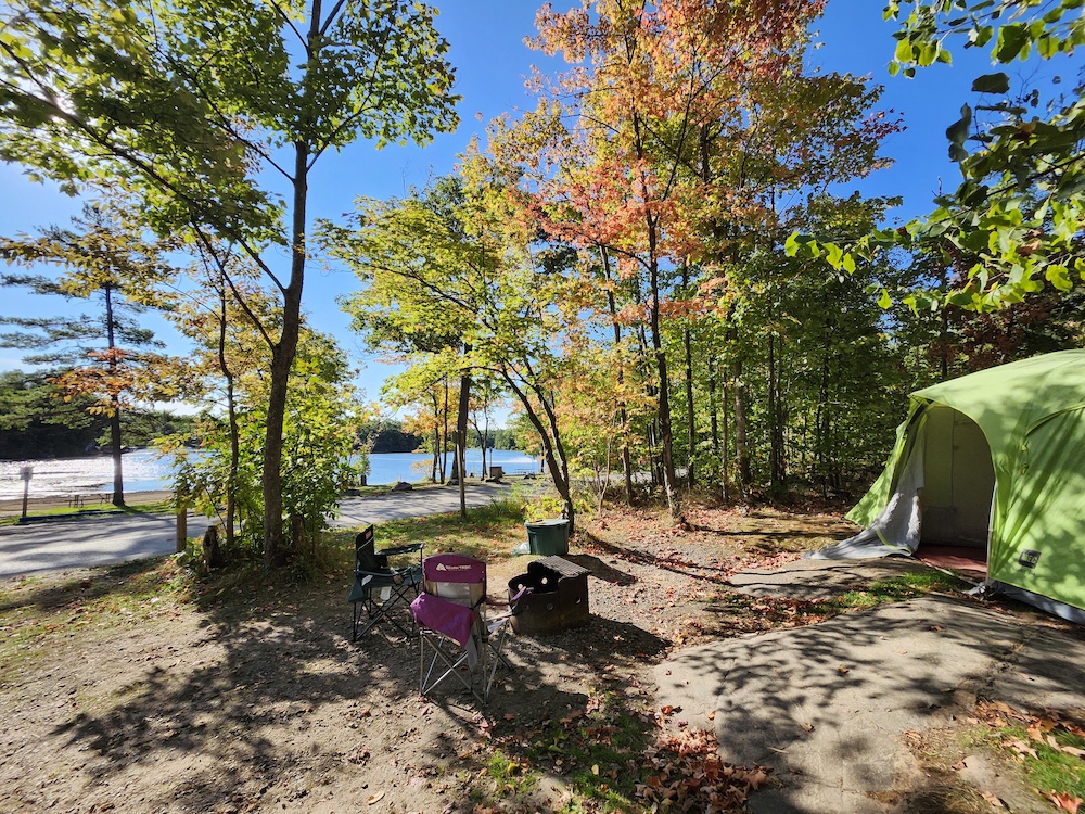 Tents and camp chairs around fire pit with fall leaves