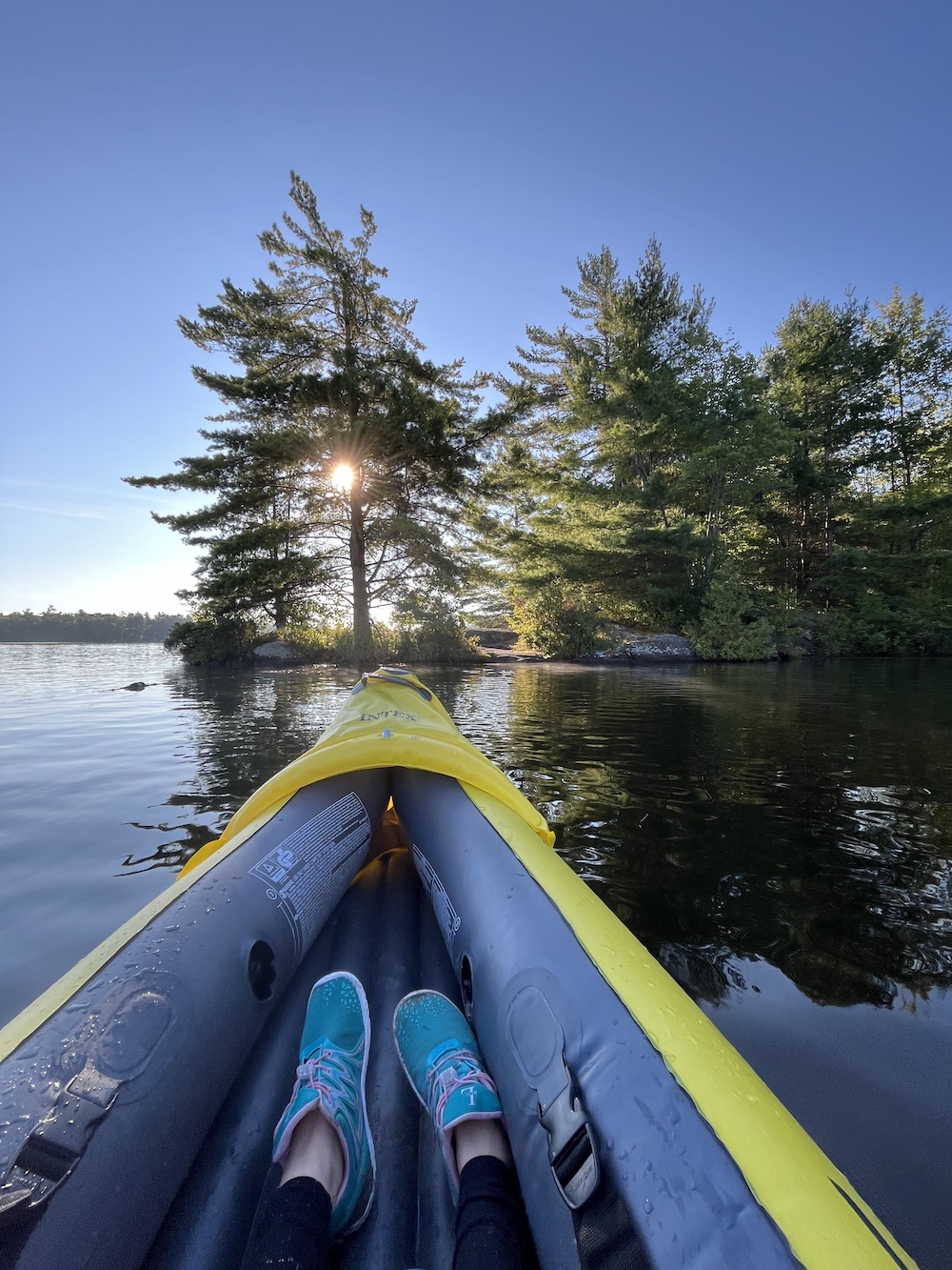 Bow of inflatable kayak on a lake with pine trees