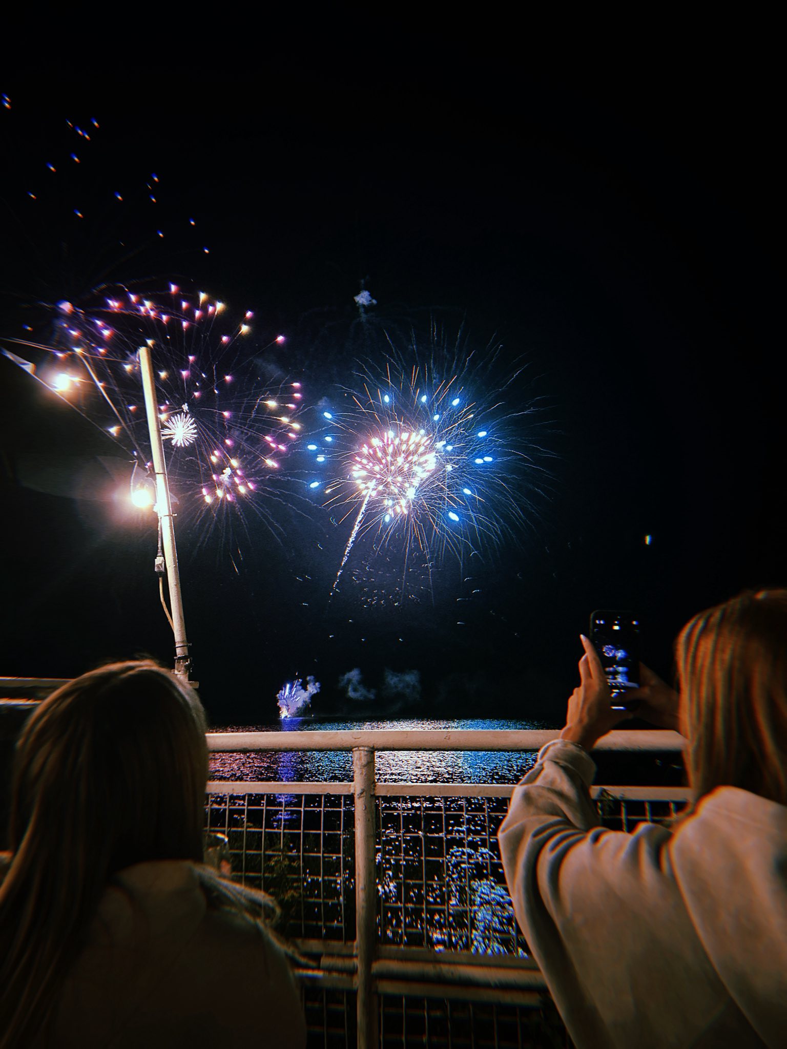 two people watch a glowing fireworks display over the lake at Shake The Lake Ribfest in North Bay.