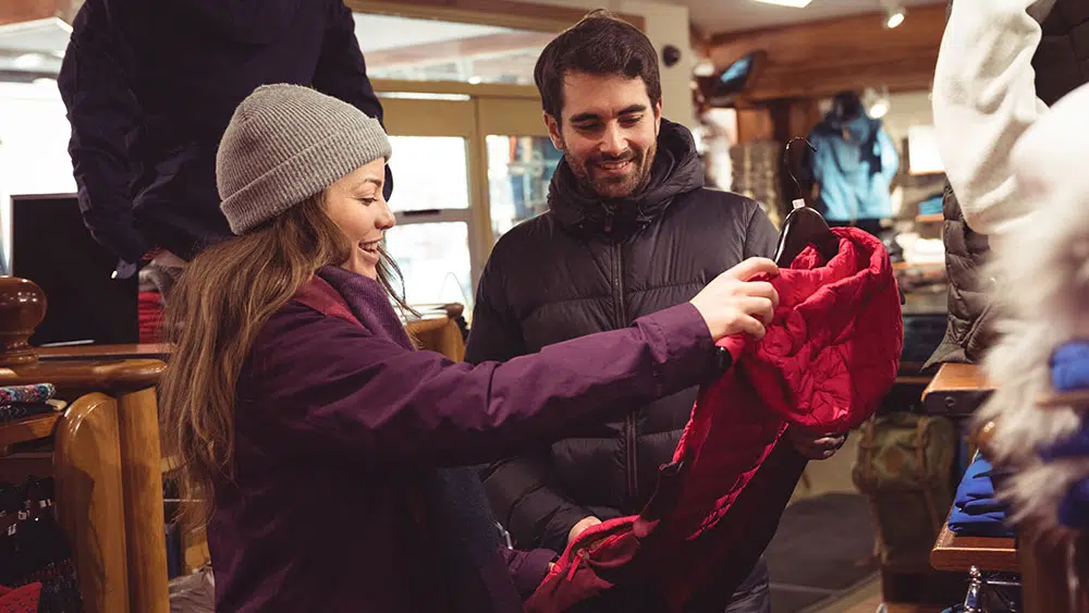 a man and woman smile and chat as they shop for winter apparel.