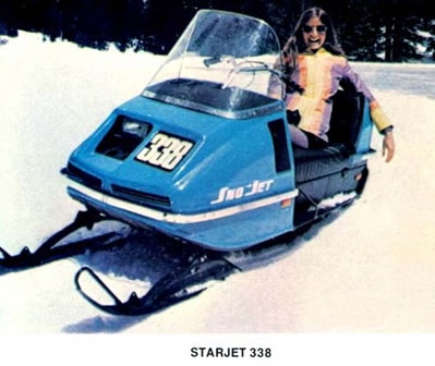a sky blue 1973 Sno-Jet Starjet, a shiny, short, boxy snowmobile with a smiling woman sitting in the seat on a sunny winter day. 