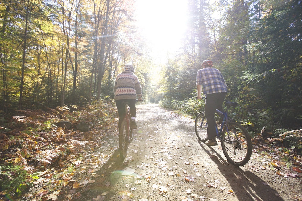 Two people biking on flat trail through the woods in Algonquin