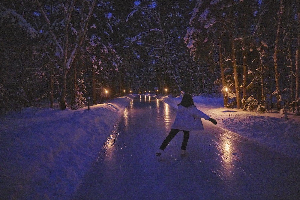 Person skating on skating trail at night lit by tiki torches