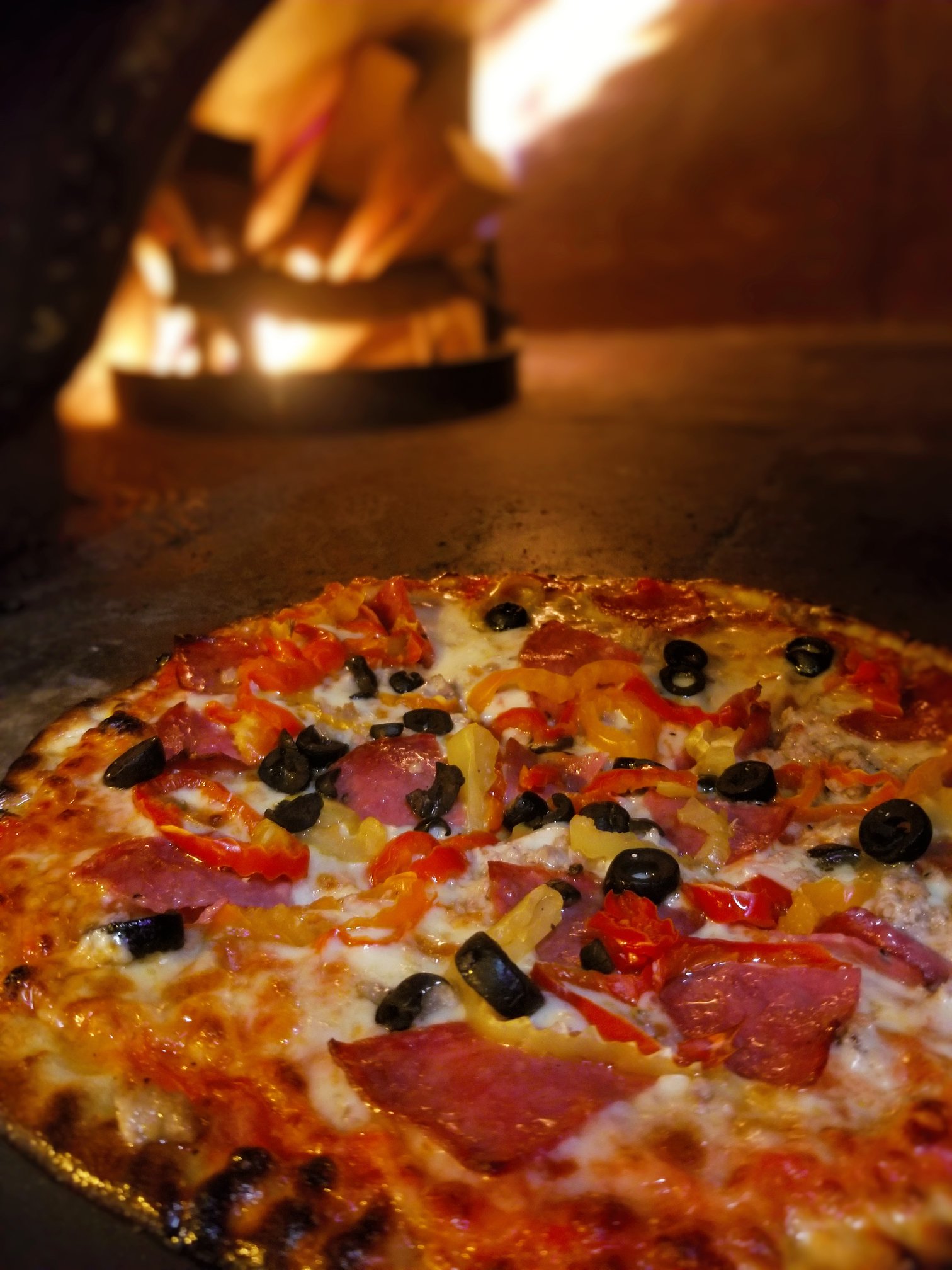 a golden pizza comes out of a glowing wood-fired oven at The Boiler Room in Sault Ste. Marie. 