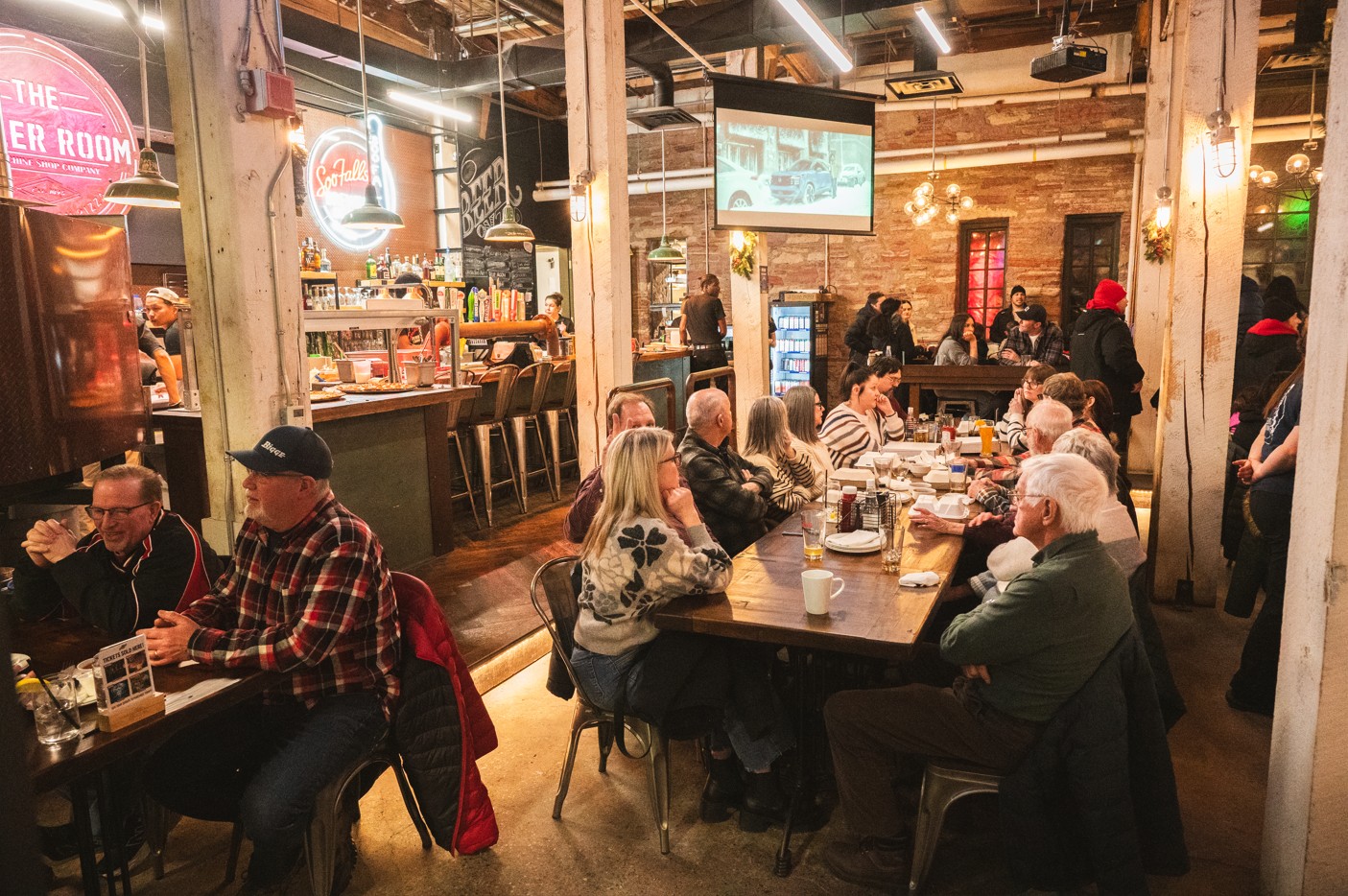 Long tables filled with happily chatting patrons in the large brightly lit brick dining room of the Boiler Room in Sault Ste. Marie. 