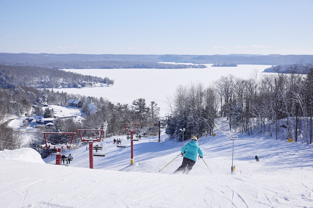 Person skiing down hill with lake in background