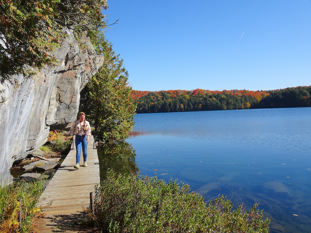 Woman walking on boardwalk next to cliff and lake