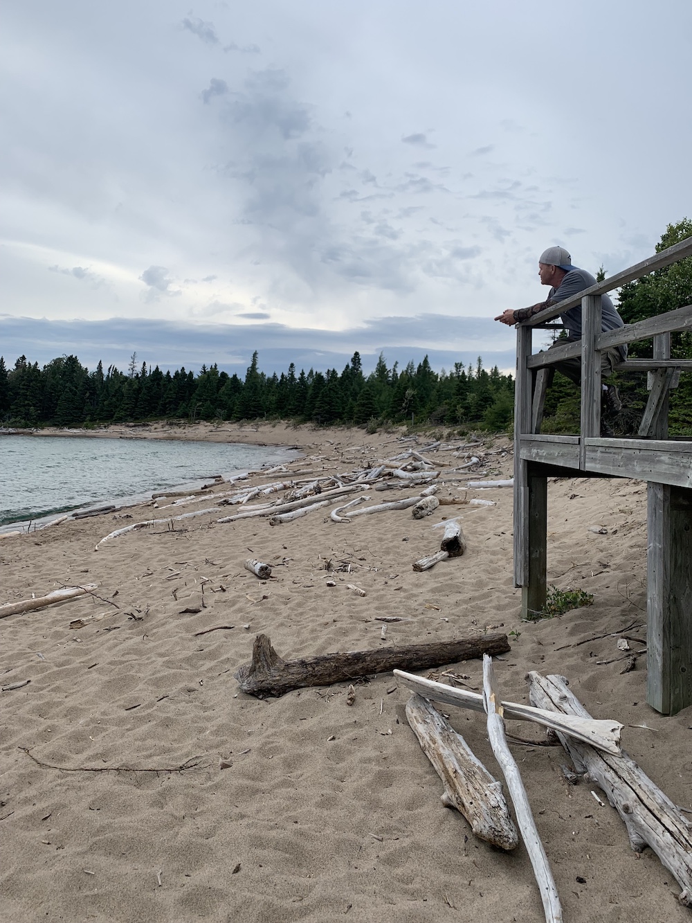 Man stands on elevated platform gazing out at water
