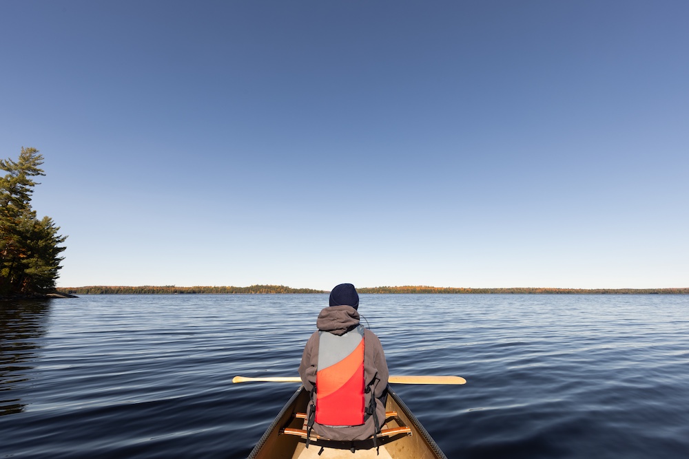 Person in bow seat of canoe on big lake
