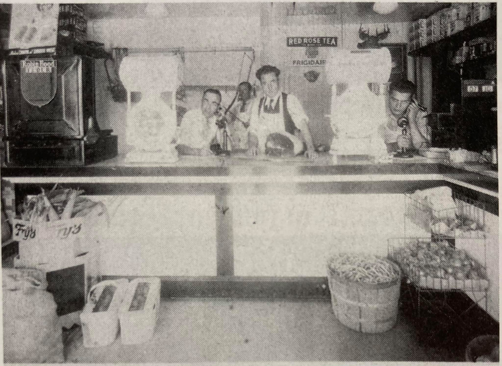 a black and white photo of four men standing behind a shop counter, busily on phones and looking hard at work at Pianosi's Meat Market in Copper Cliff in 1937.