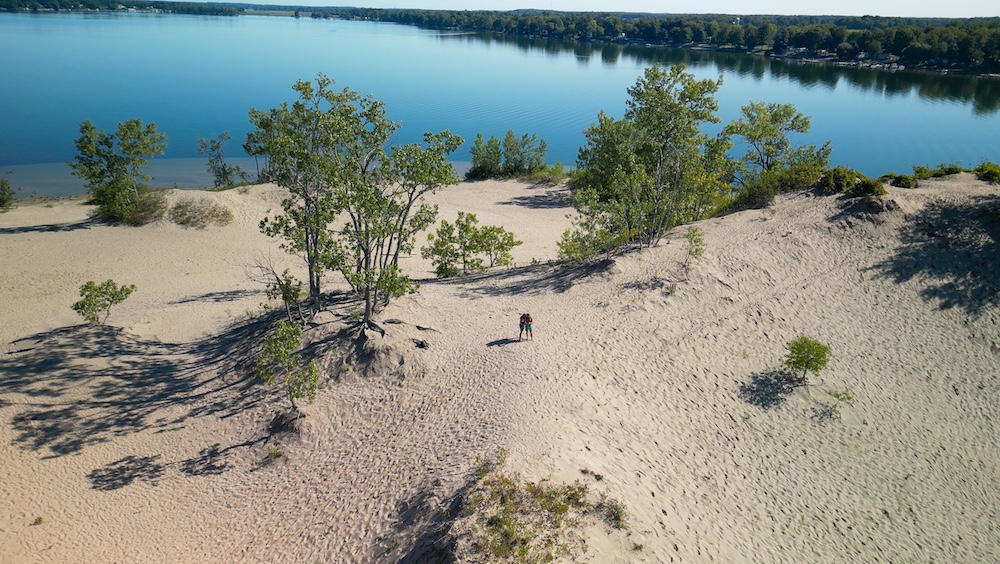Two people stand on sand dunes 
