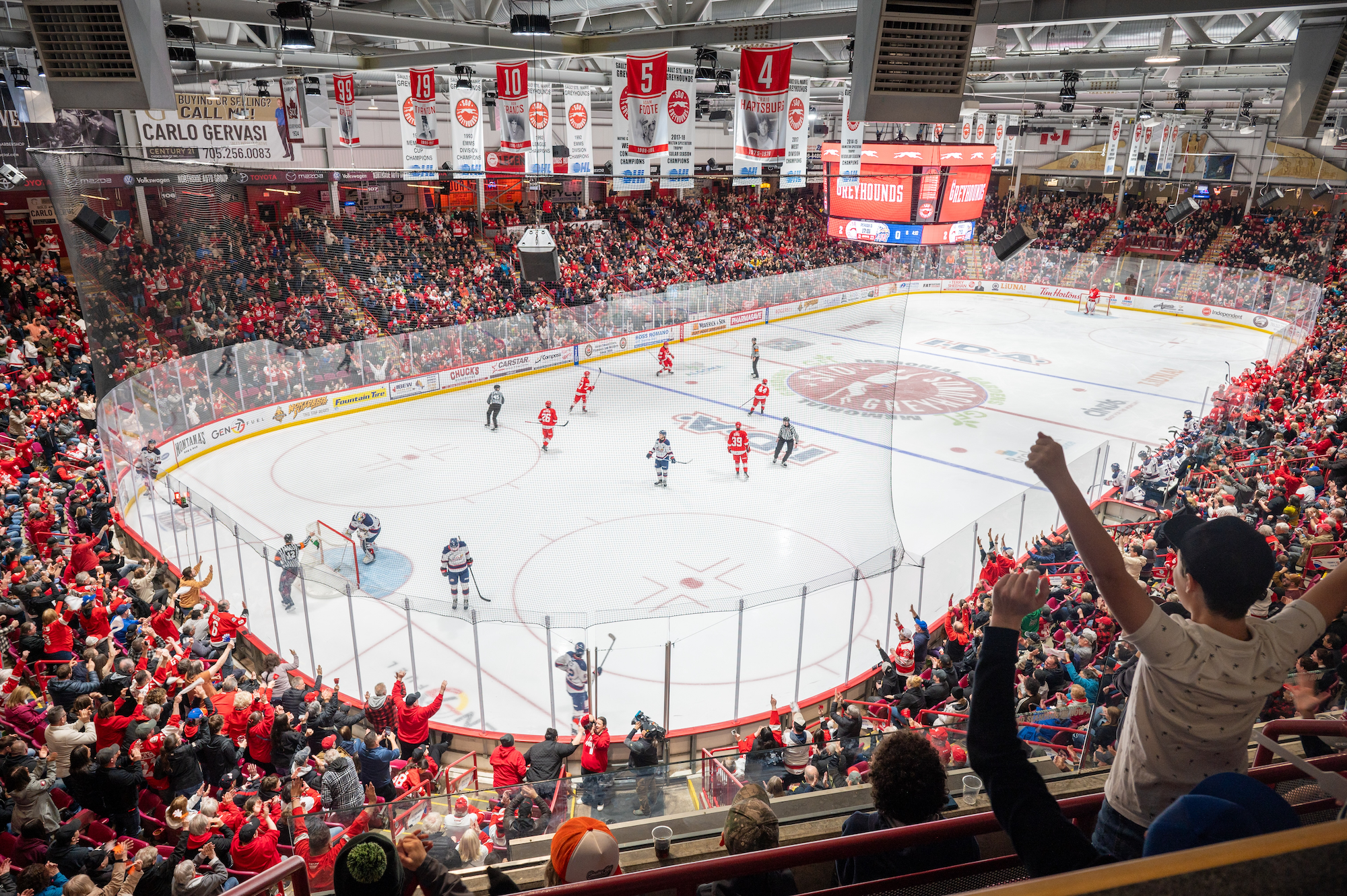 a hockey arena filled to capacity with fans watching the game in Sault Ste. Marie. 