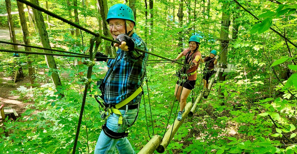 Three people on high ropes course through the woods