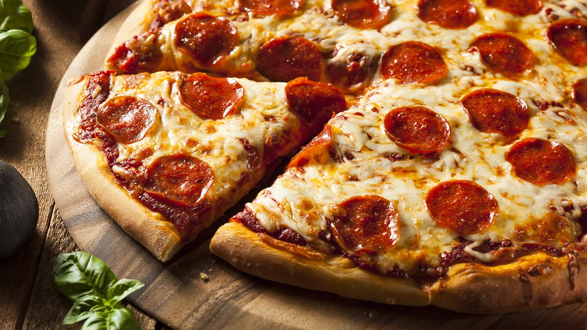 Cheesy pepperoni pizza with a traditional crust garnished with fresh basil from Aurora's. 