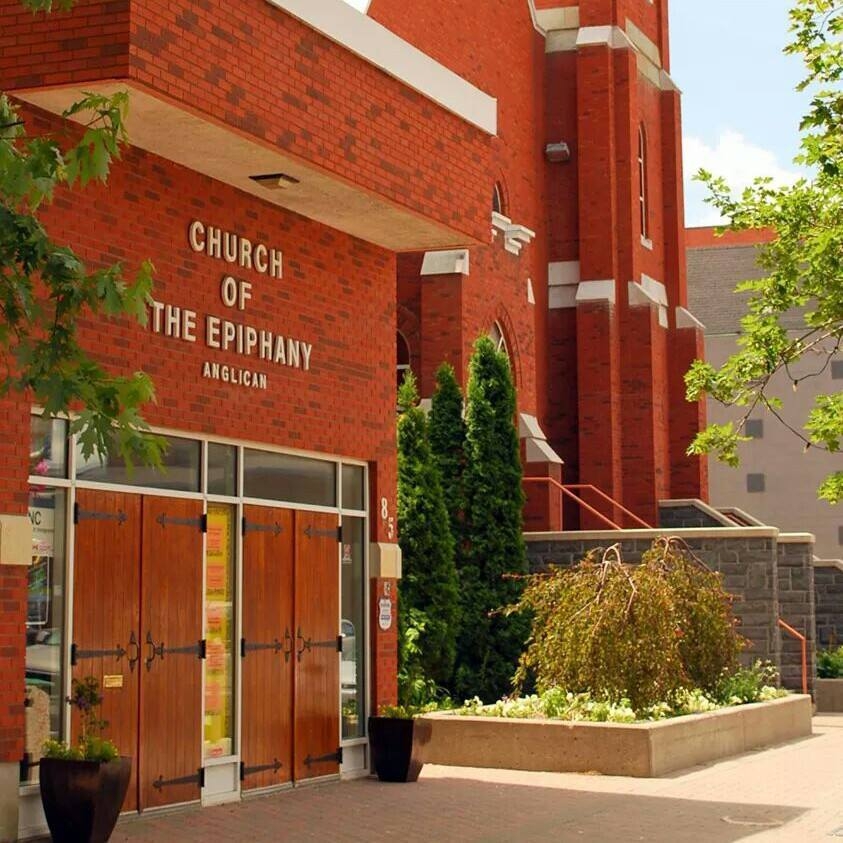 The Church of the Epiphany in Sudbury, Ontario, a tall red brick church with stained glass windows and square-cornered towers in an early 20th century ecclesiastical style.