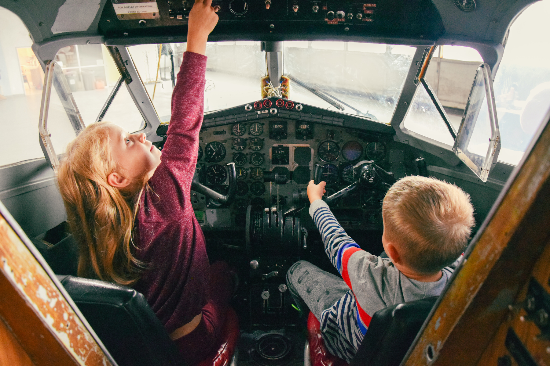 two small children flick switches and pretend to steer in the cockpit of a small plane at the Canadian Bushplane Heritage Centre. 