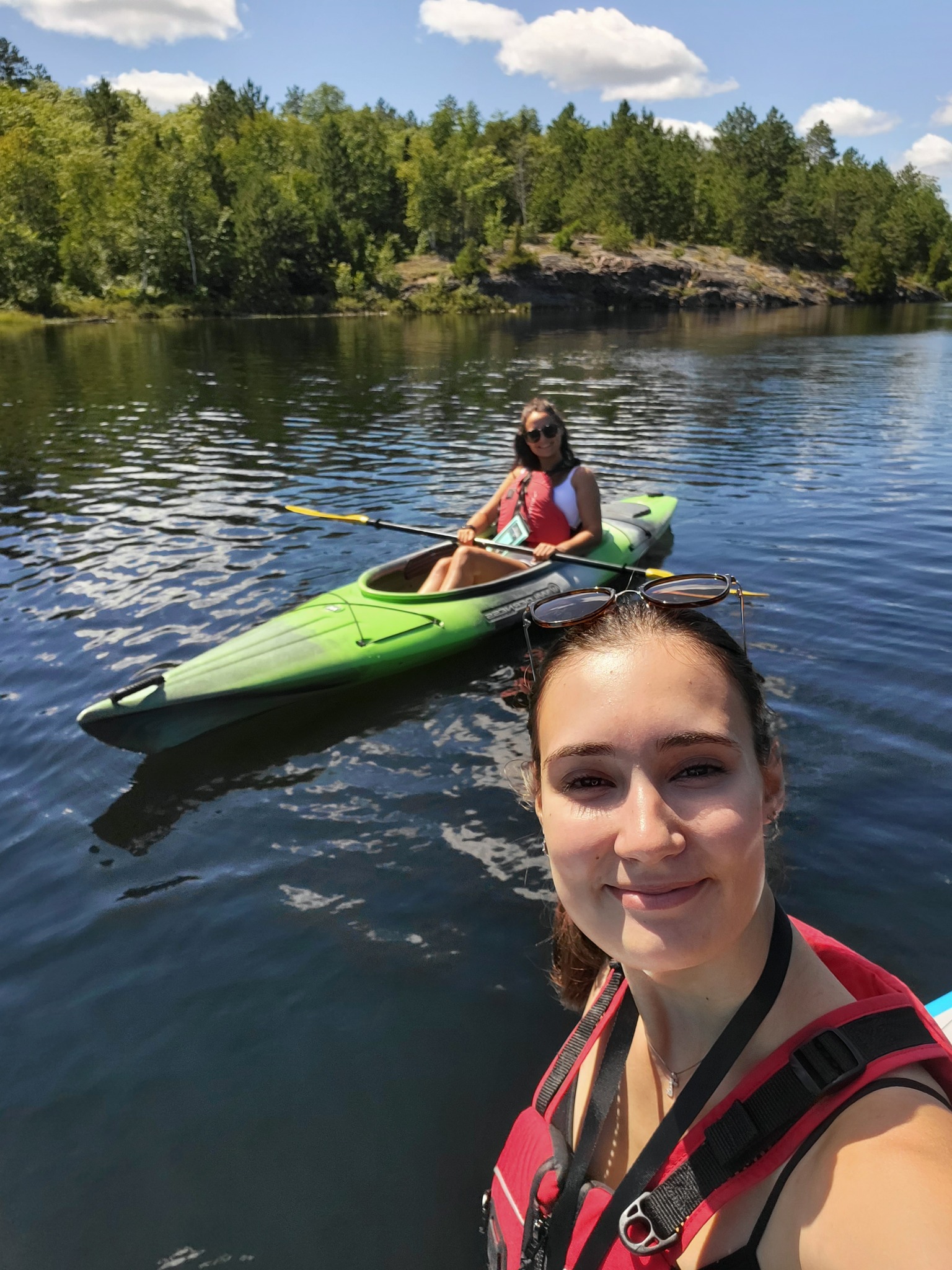two smiling women in kayaks stop for a picture on a sunny summer day on Crowley Lake in Sudbury. 