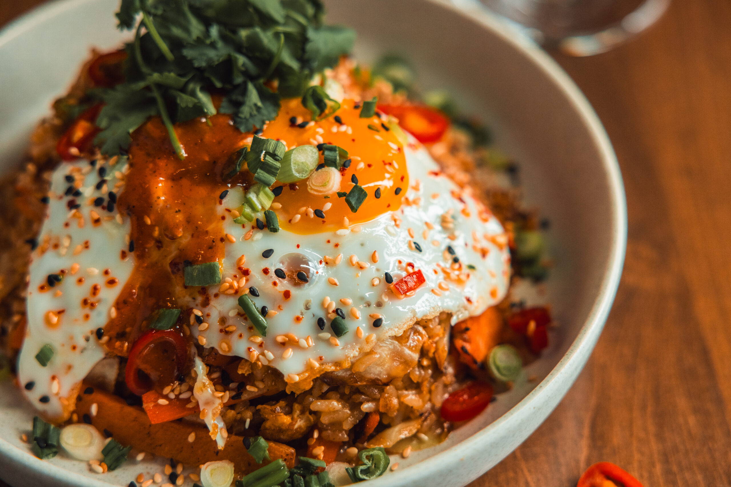 a spicy rice dish from Peace Restaurant, topped with green onion, diced red pepper, kale, sesame seeds and a fried egg. 