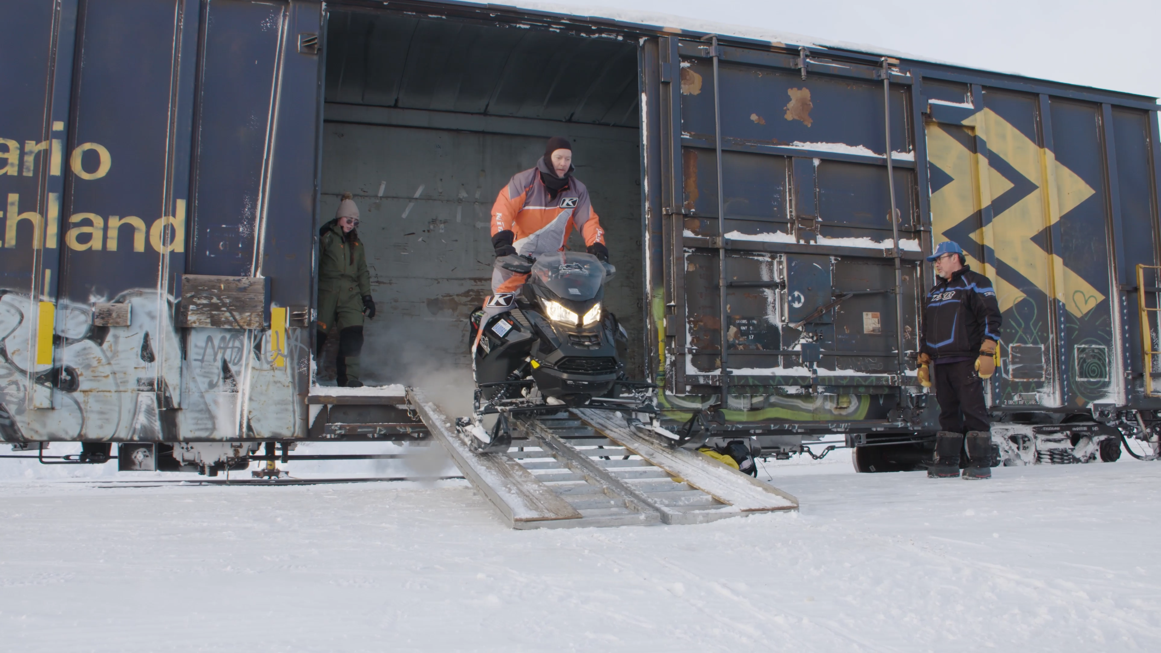 Eric Ménard drives his snowmobile down the ramp off the Ontario Northlander train car, while Mylène Coulombe-Gratton of Follow Her North follows behind.