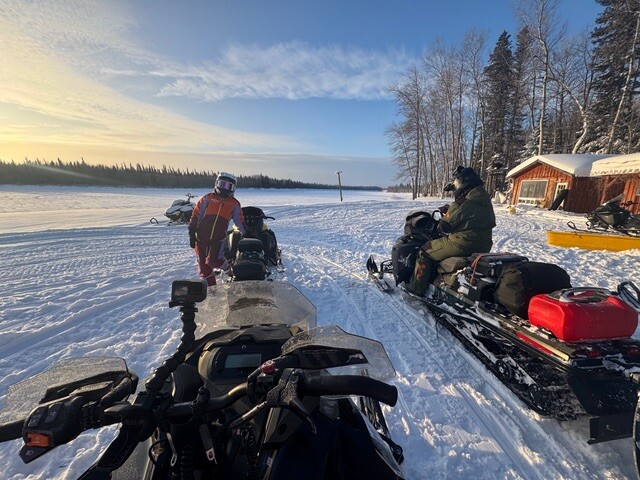 Eric Ménard and Mylène of Follow Her North pose next to their snowmobiles st sunrise at Camp Onakawana on the way to James Bay.