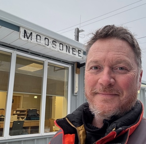 Eric Ménard smiling in front of the Moosonee Station in winter. 