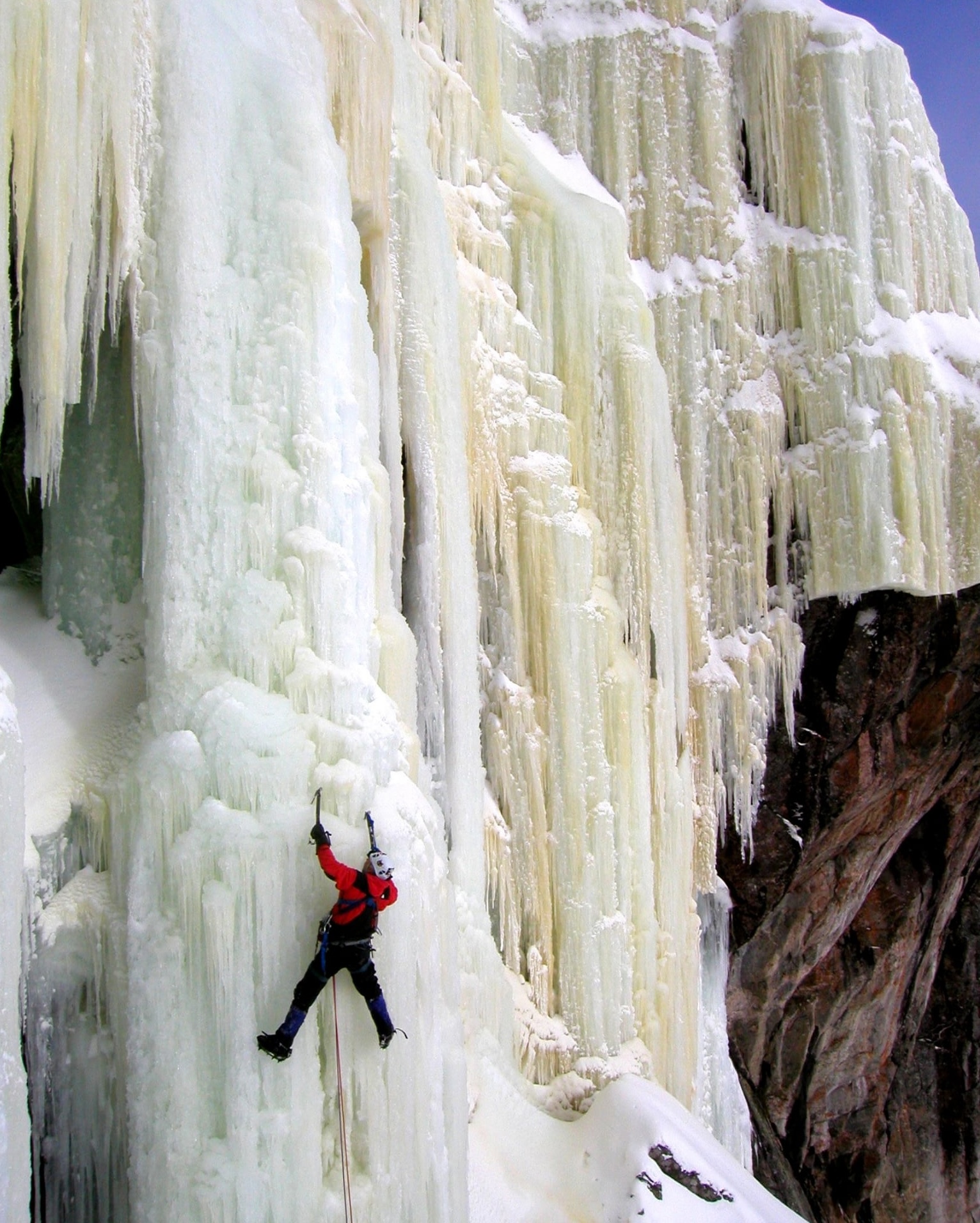 a person scaling a towering frozen waterfall with ice picks near Sault. Ste. Marie, Ontario. 