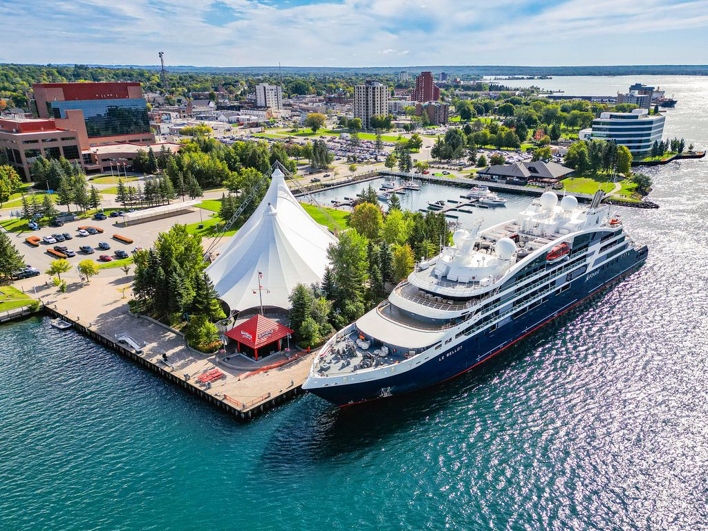 a large cruise ship docked in turquoise water next to the white canvas spire of the Roberta Bondar Pavilion in the summer.  
