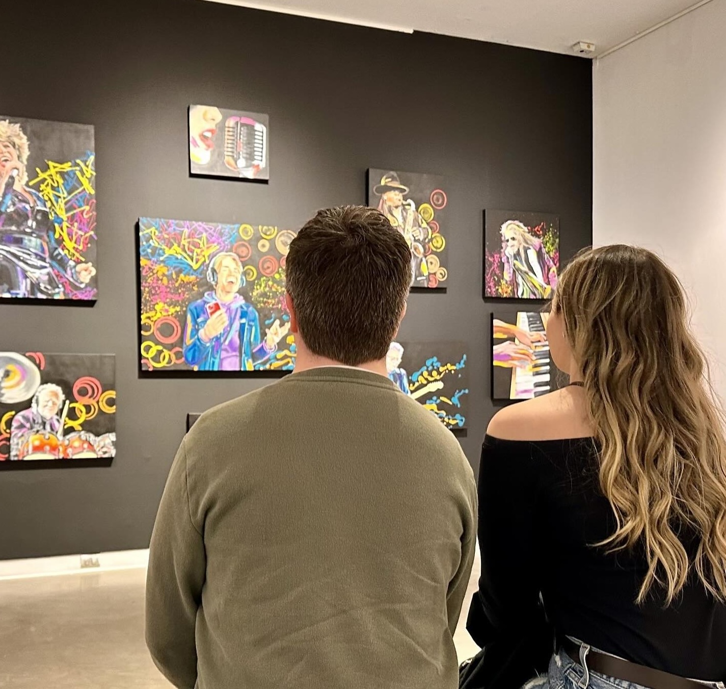Two people sit on a bench at WKP Gallery in North Bay, gazing at the art displayed on the walls.