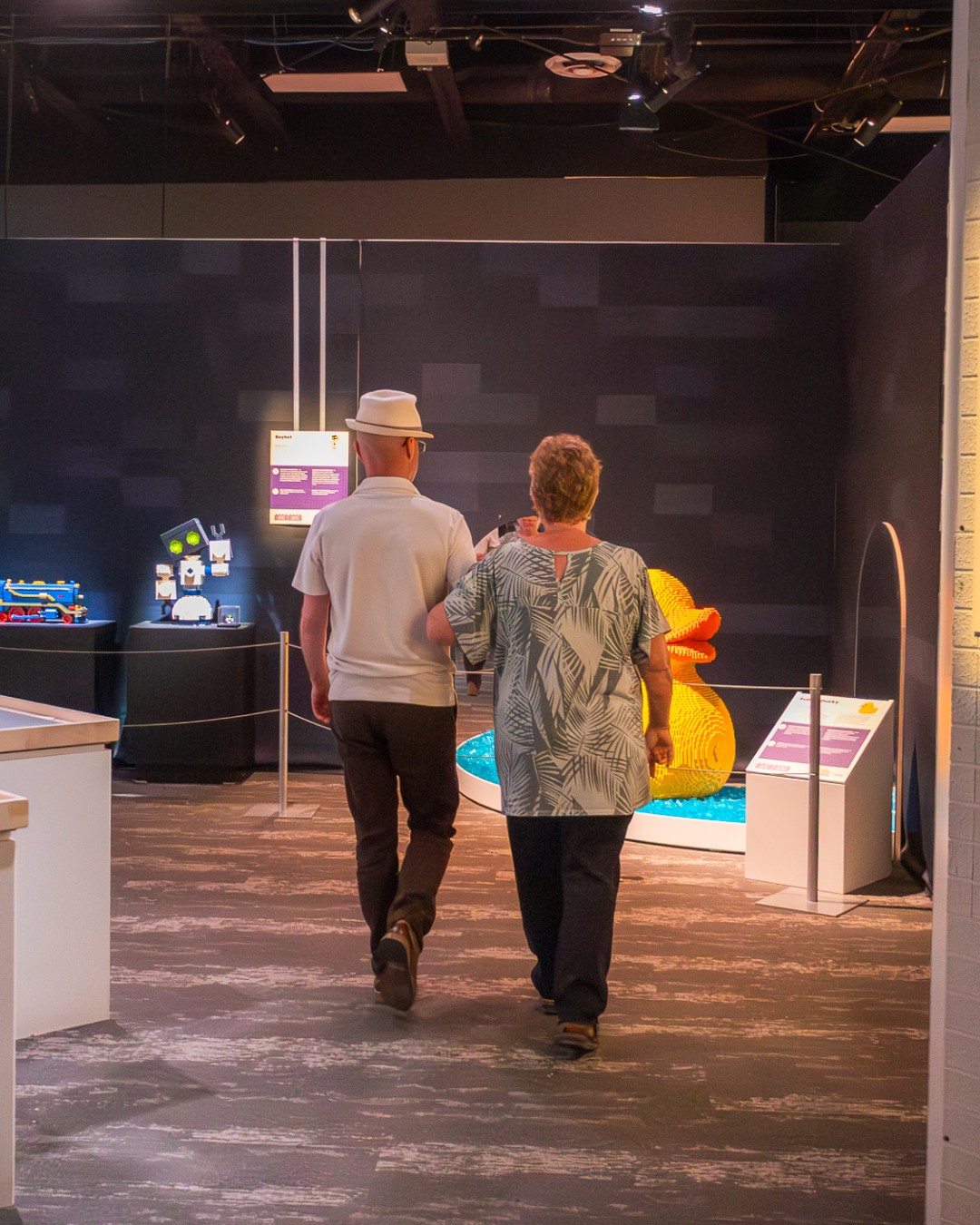 an older man and woman stroll together through an exhibit room in Science North.