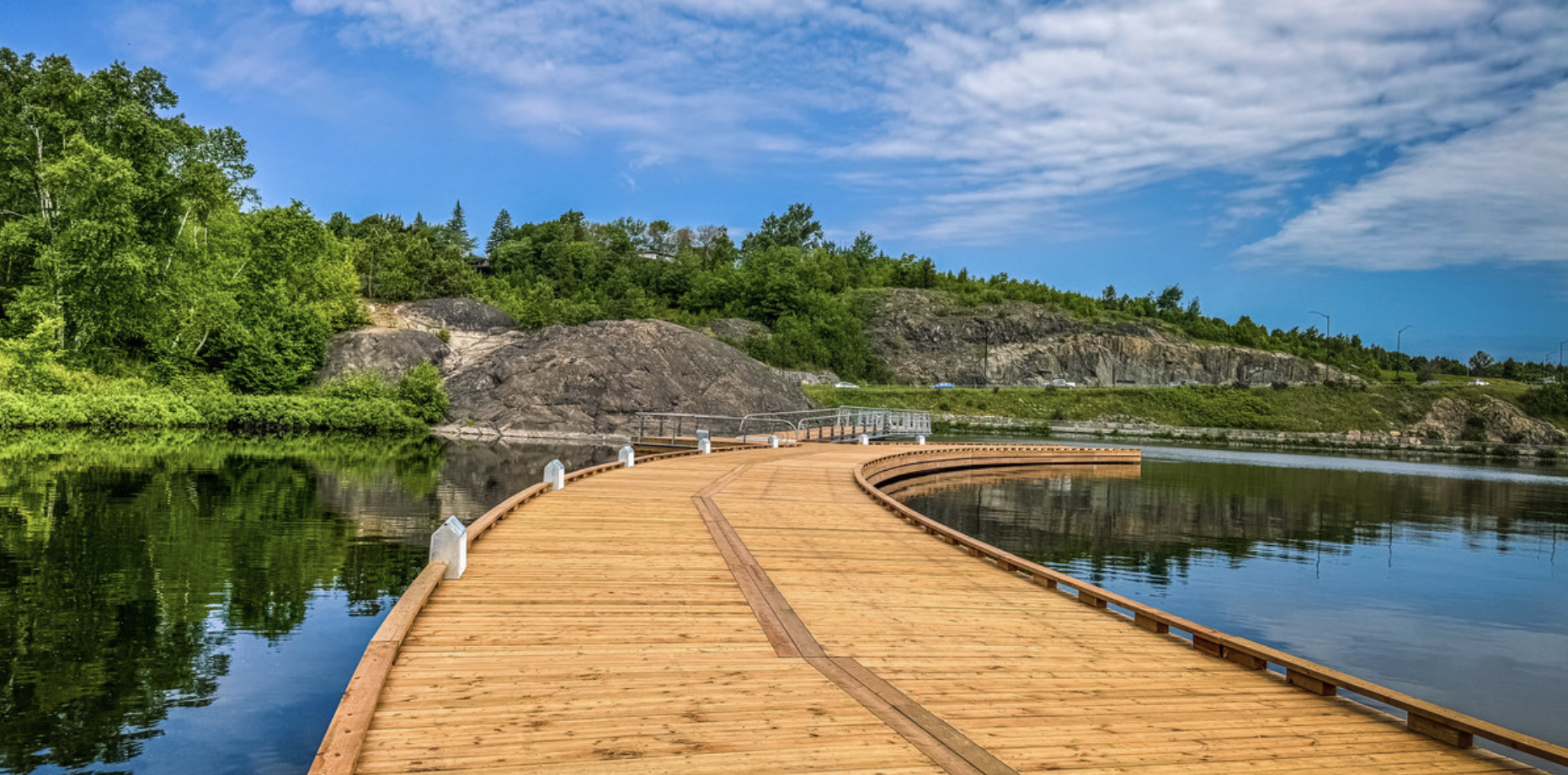 the wide smooth wooden Bell Park Walkway that stretches over the water of Ramsey Lake in Sudbury.