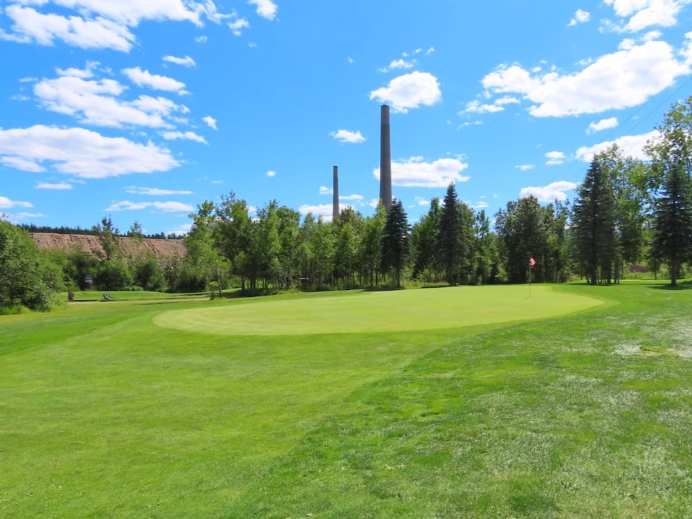 Golf course with smoke stacks in background