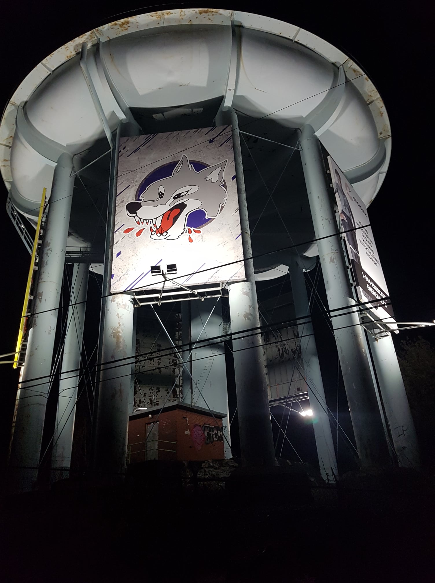 the Sudbury water tower lit up at night with a Subury Wolves banner hanging below it. 