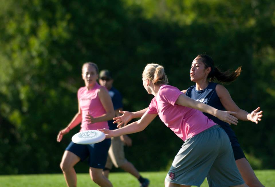 a team plays ultimate frisbee in a lush grassy field on a summer day in North Bay.