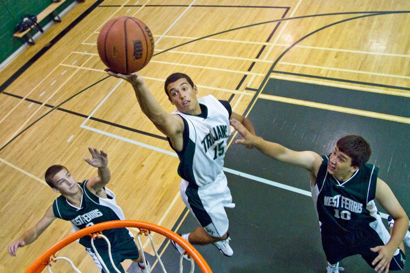 The West Ferris basketball team members leap to stop an opponent's shot.