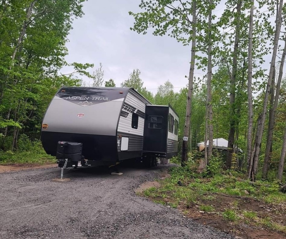 a large RV tucked into a smooth, lushly forested campsite at Mattawa River Resort.